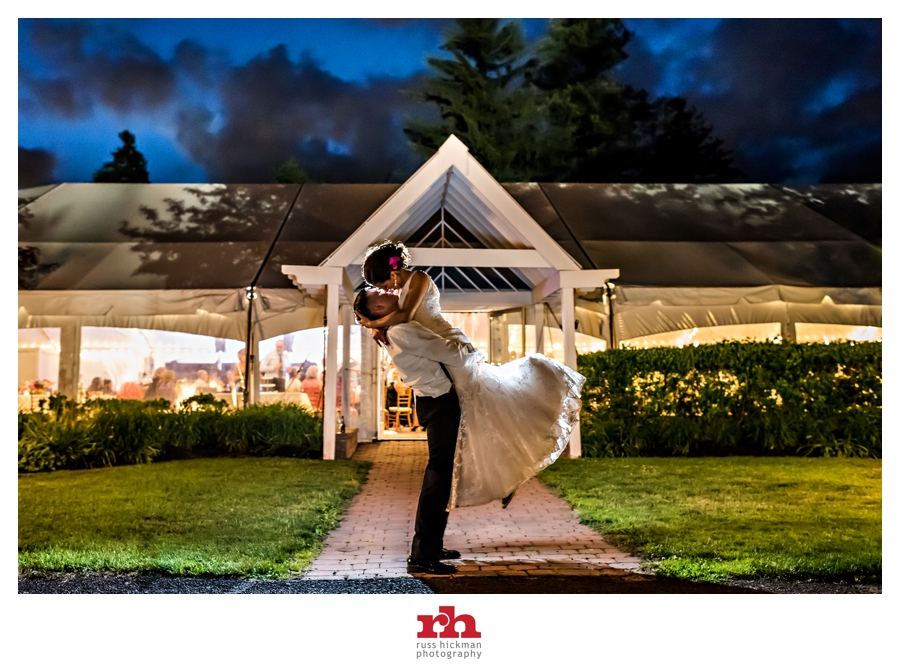 A Groom lifts his Bride in the air for a kiss if front of the reception tent at Pearl S Buck Estate Wedding.